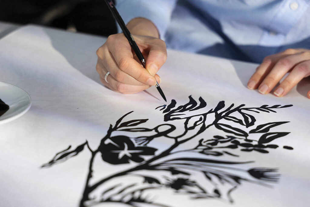 a person drawing the la perle pattern for arte