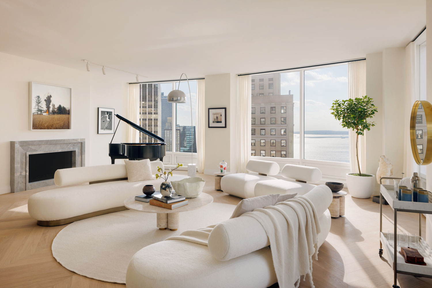 A bright living room with curved white couches and city views