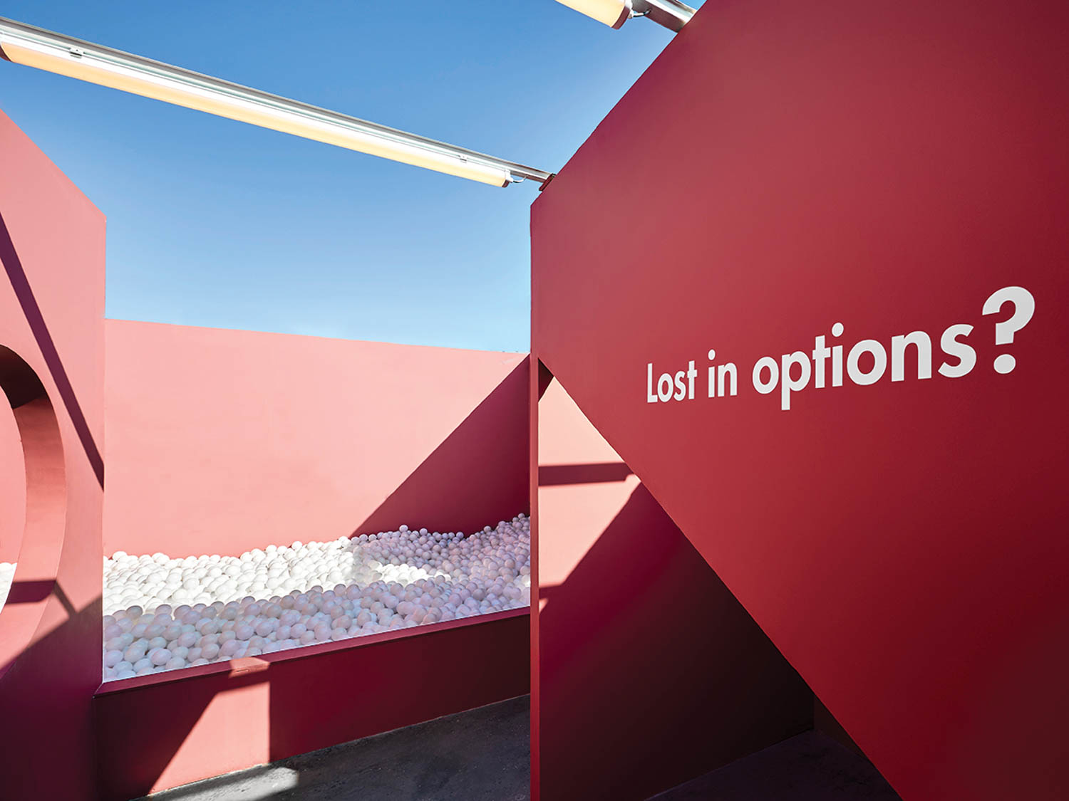 a pink wall that says "Lost in Options" near a white ball pit