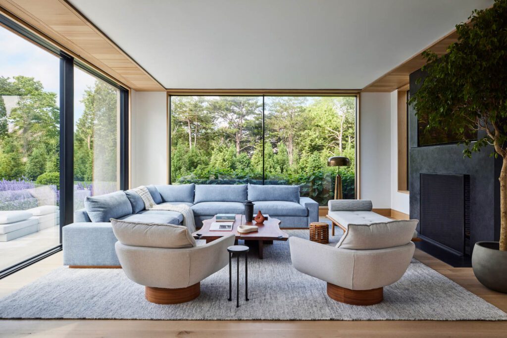 Coastal interior design is shown in this family room with a custom blue sofa and white chairs