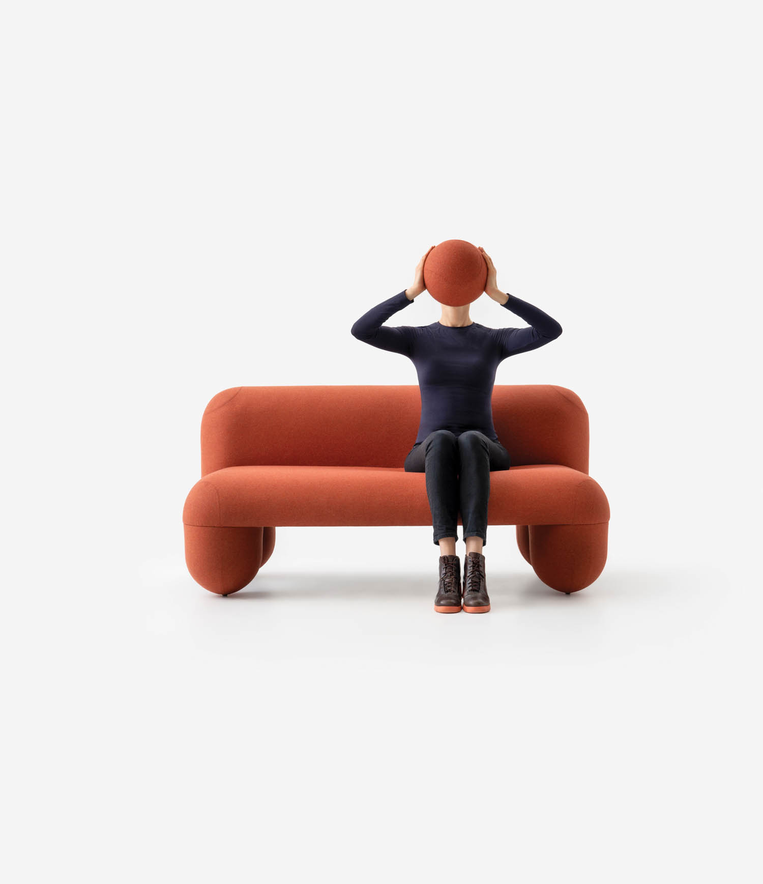 person sitting on an orange couch with an orange ball in front of face