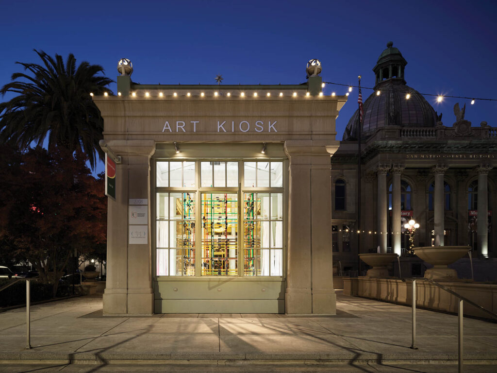 facade of a gallery at night with art visible in window