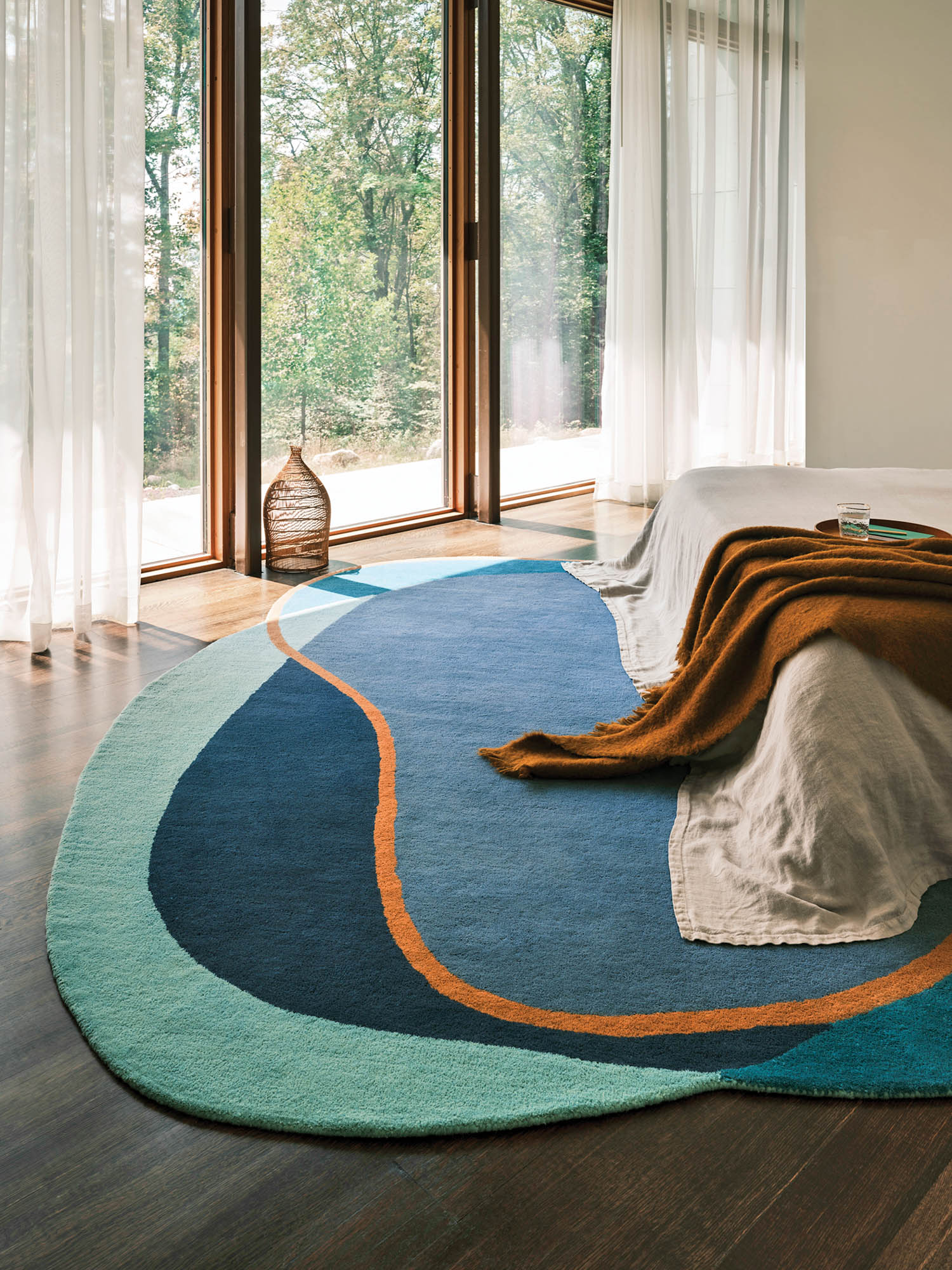 a round rug with blocks of blue and green hues and an orange border