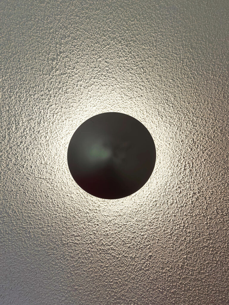 a disco sconce in black illuminates the wall