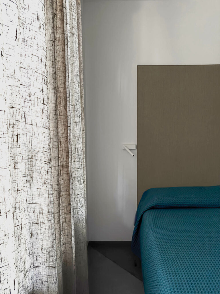 A raw linen curtain and Omar Carraglia’s Mira sconce in a bedroom.