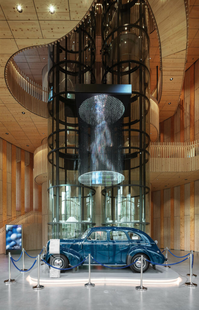 A vintage Volvo sits at the base of the principal elevators in glass tubes