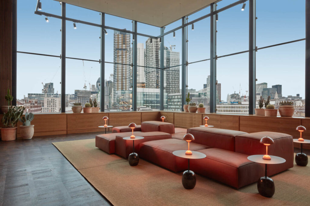 large room with dark red sofas and wide views of the city