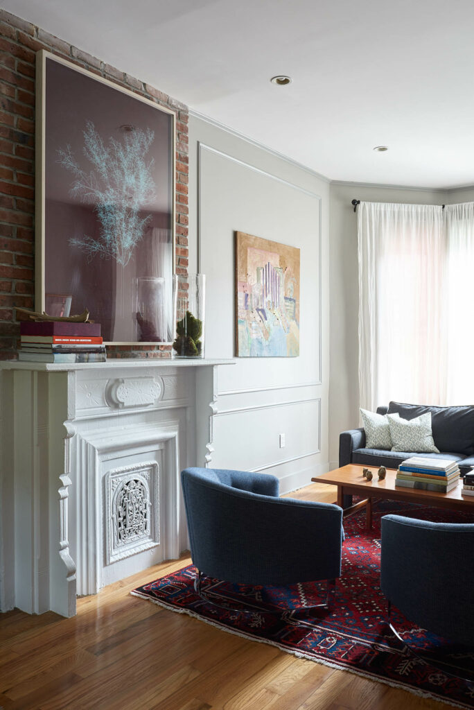 living room with dark blue velvet armchairs, artwork and detailed crown molding on fireplace