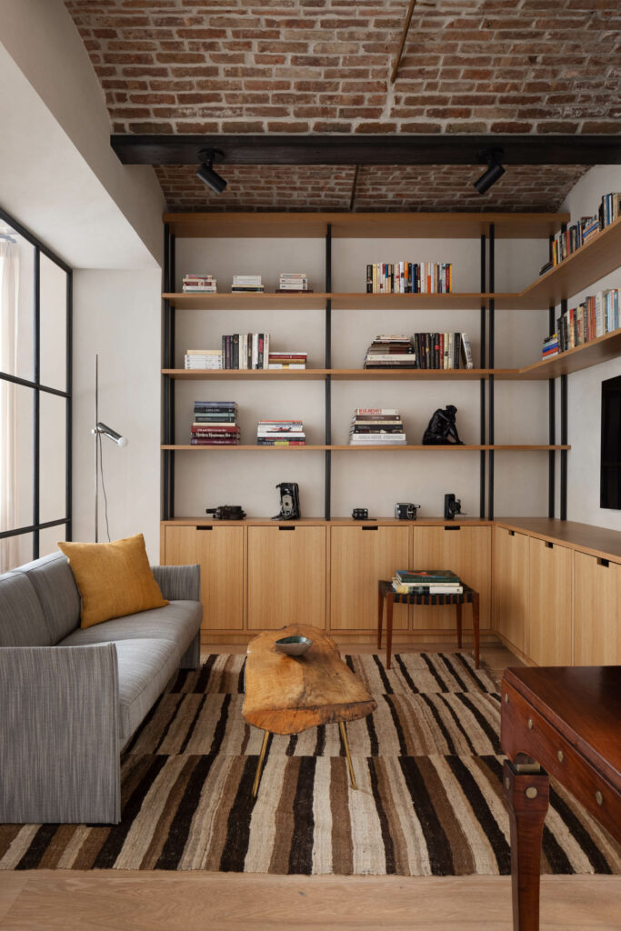 media room area with wooden accents, dark grey couch and wooden flooring