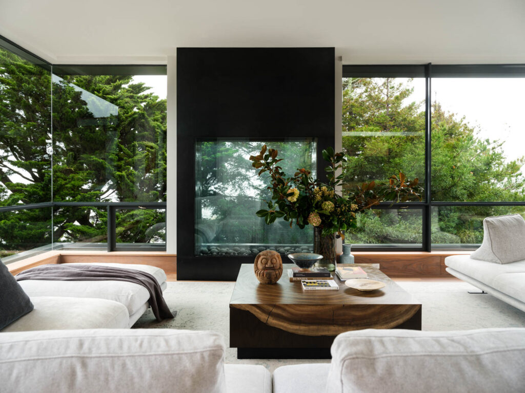 living room with white couches and floor-to-ceiling windows facing the trees