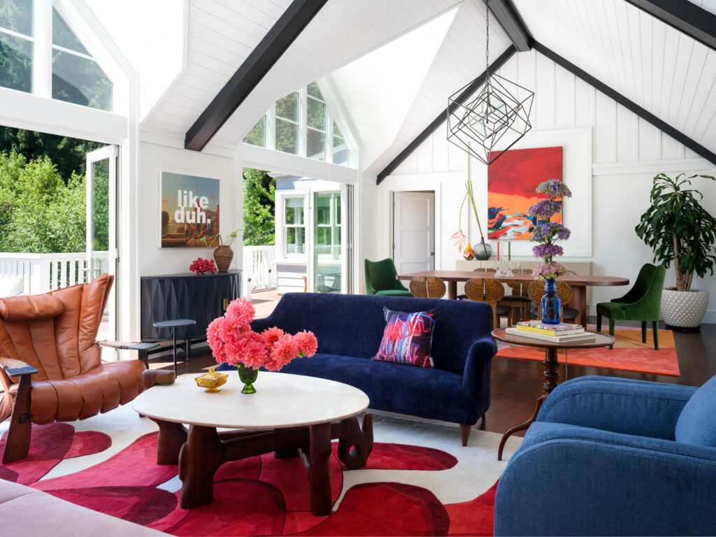 living room with a pointed ceiling, colorful armchairs and rug and lots of light