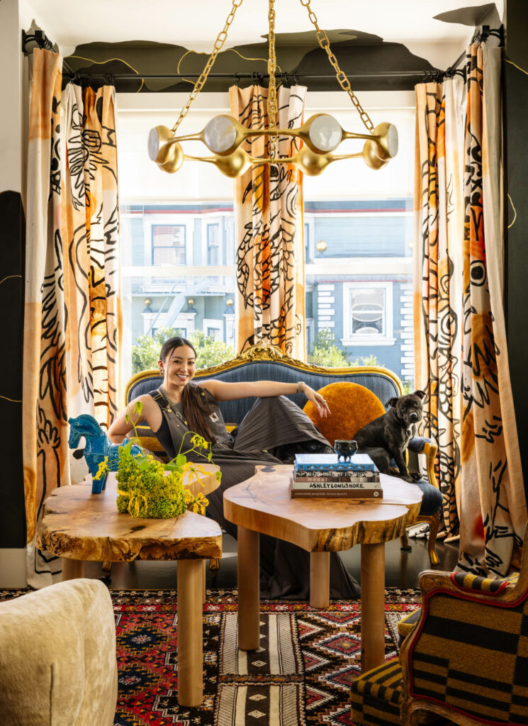 Noz Nozawa sitting on couch underneath a golden chandelier