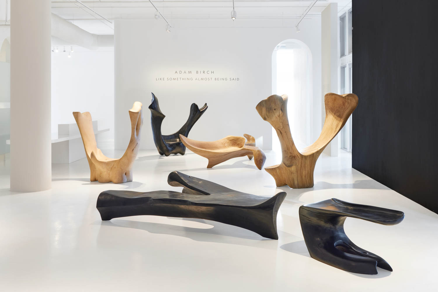 black and tan sculptures all posed in a gallery with some lying down