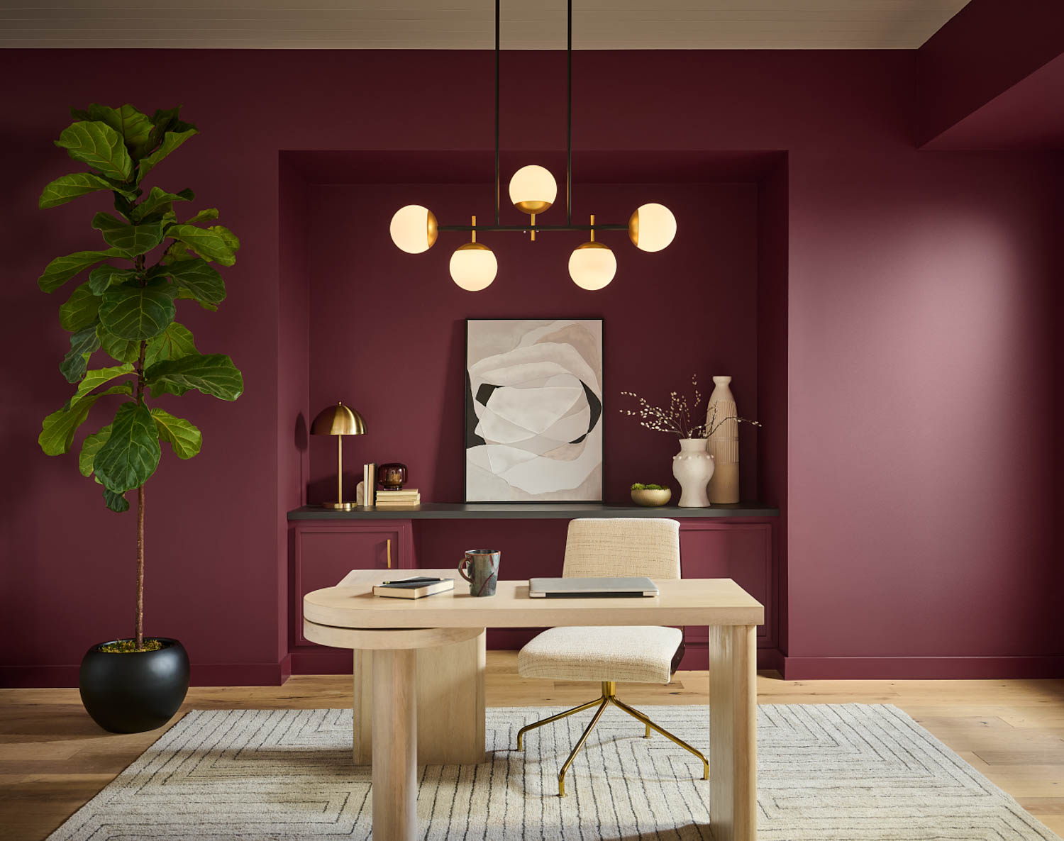 home office with dark red walls, wooden desk and chandelier