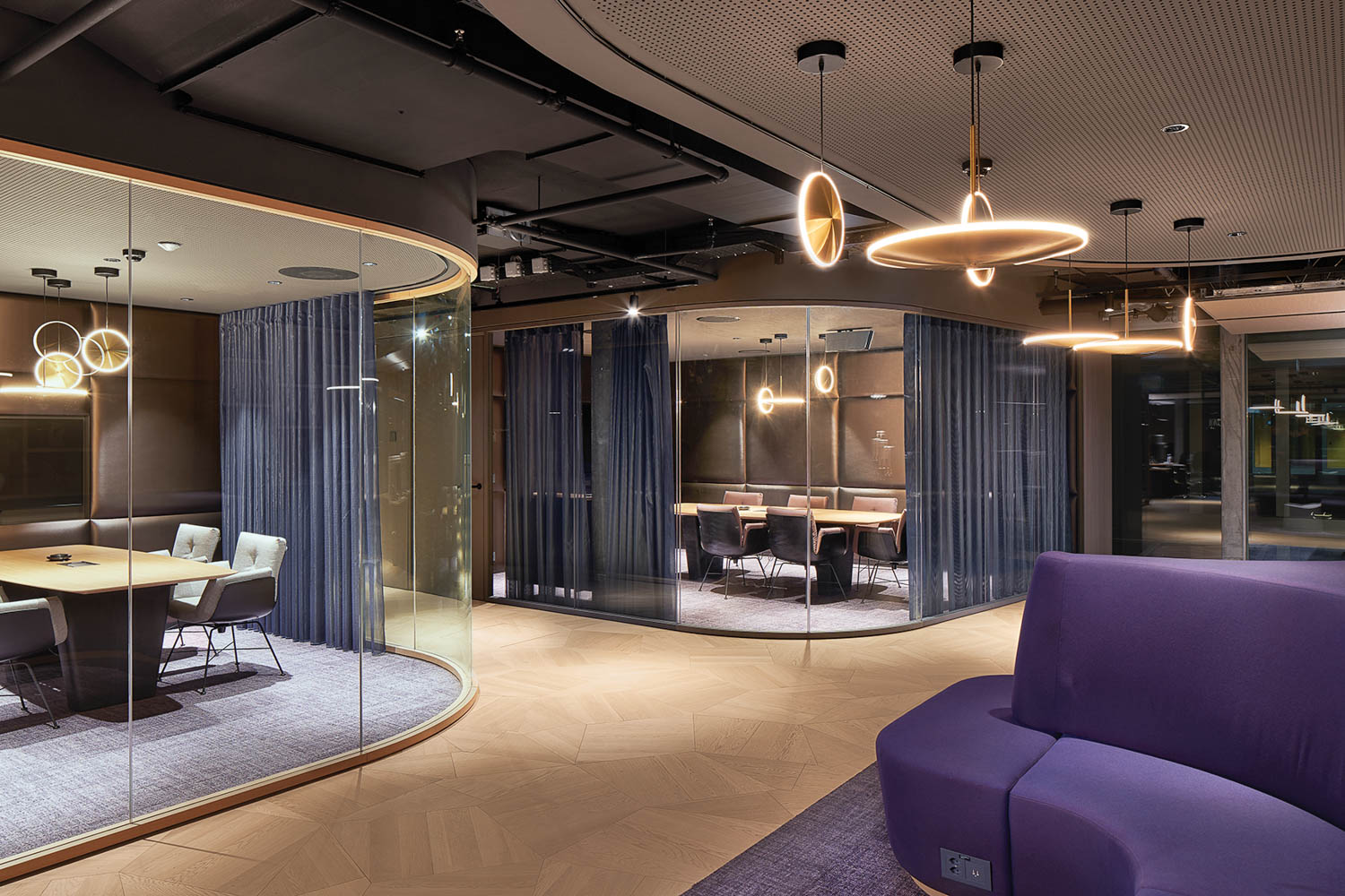 view into the conference rooms with blue drapes, sleek lighting and curved glass walls