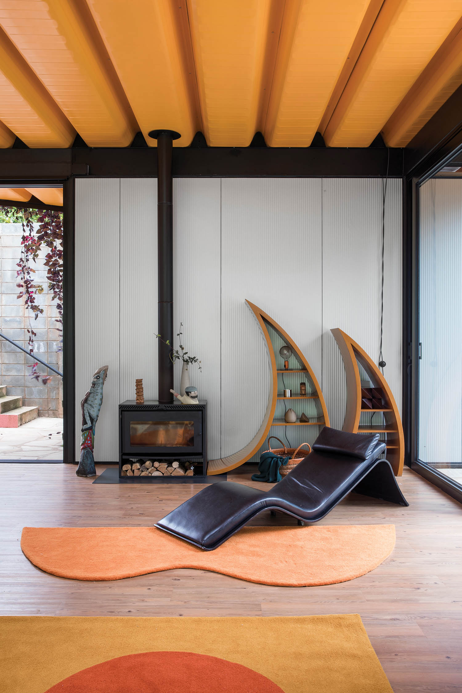 living area with bright orange rugs, curved black armchairs and curved shelves