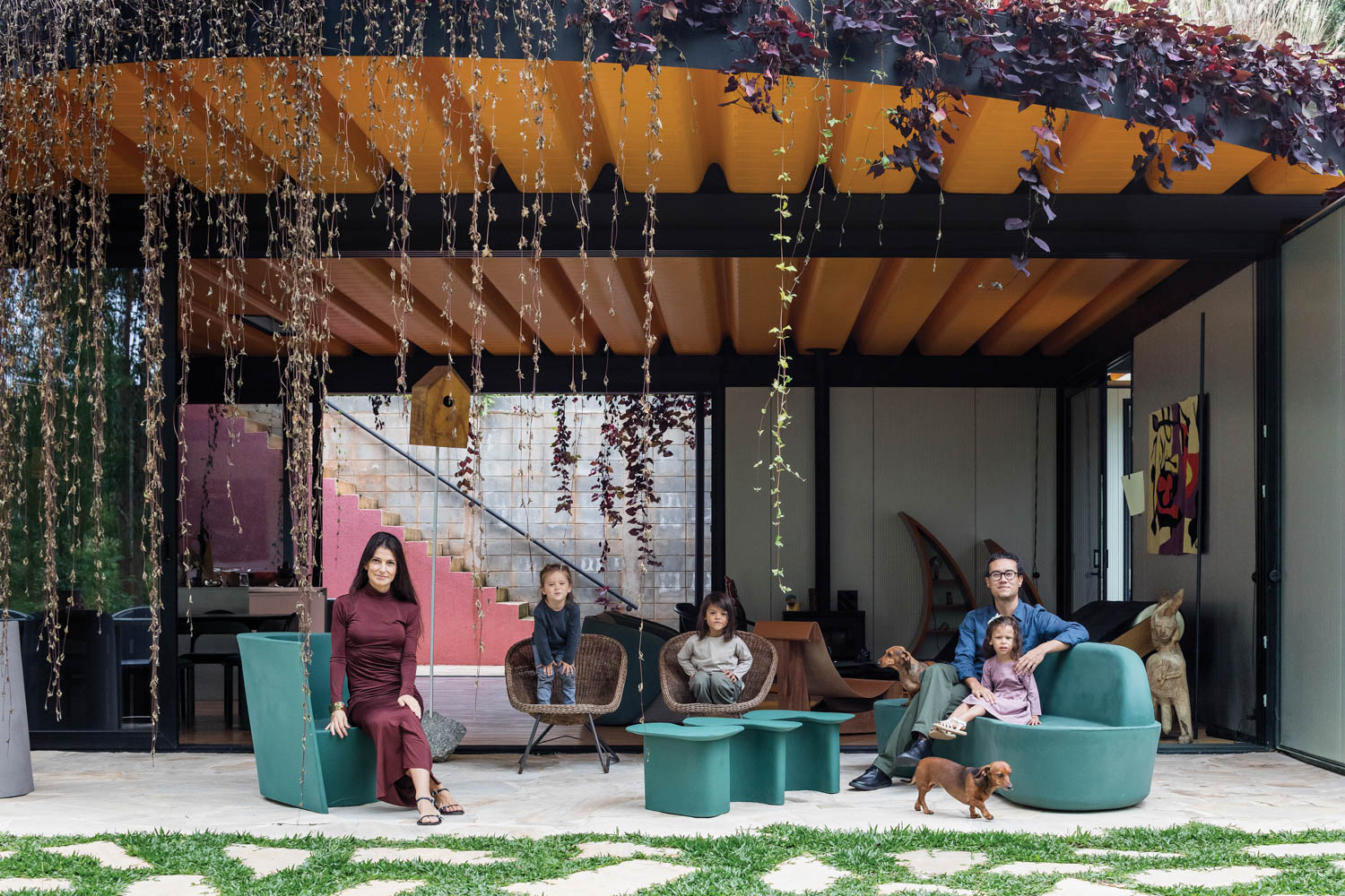 a family sits on the teal green chairs in the outdoor patio