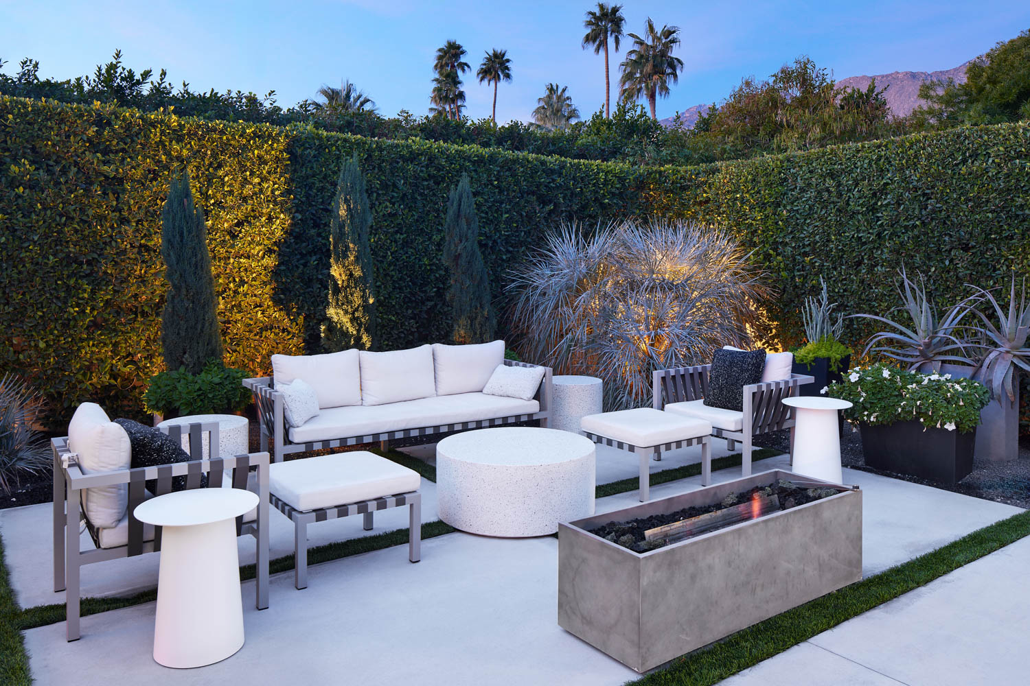 garden space has all white outdoor seating area with fireplace