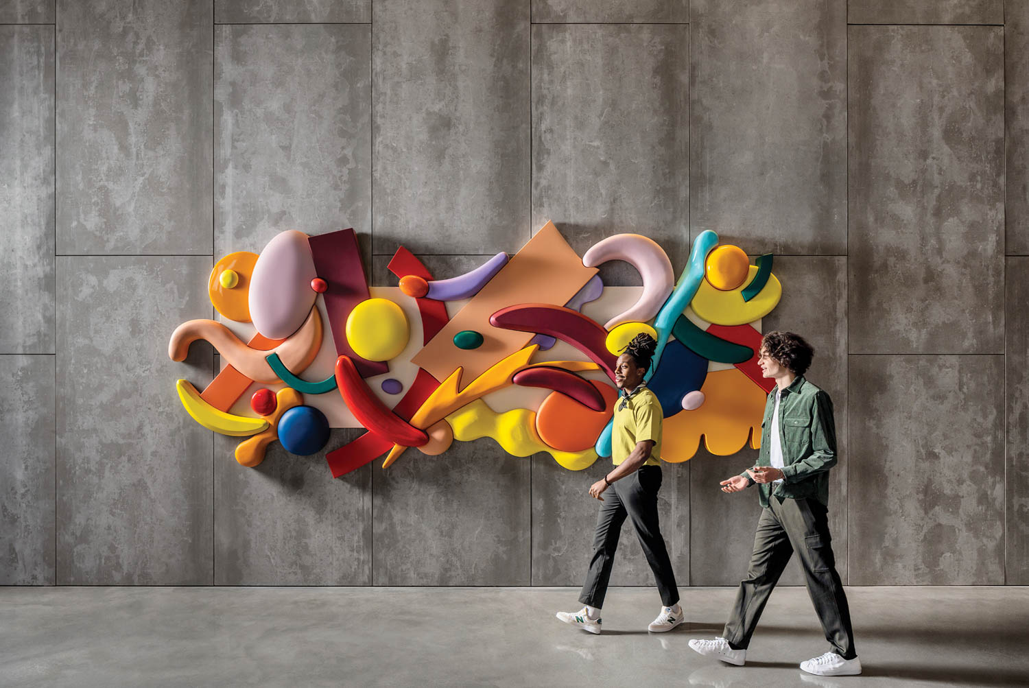 people walking in front of a colorful 3-D wall installation