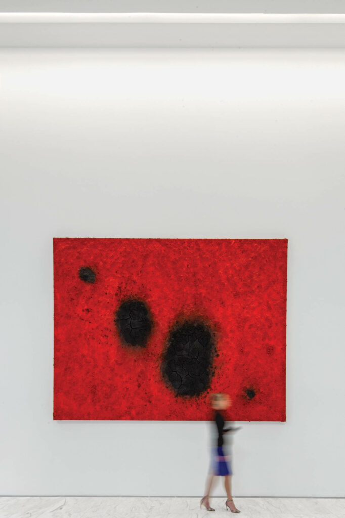 person walking by a tall red painting