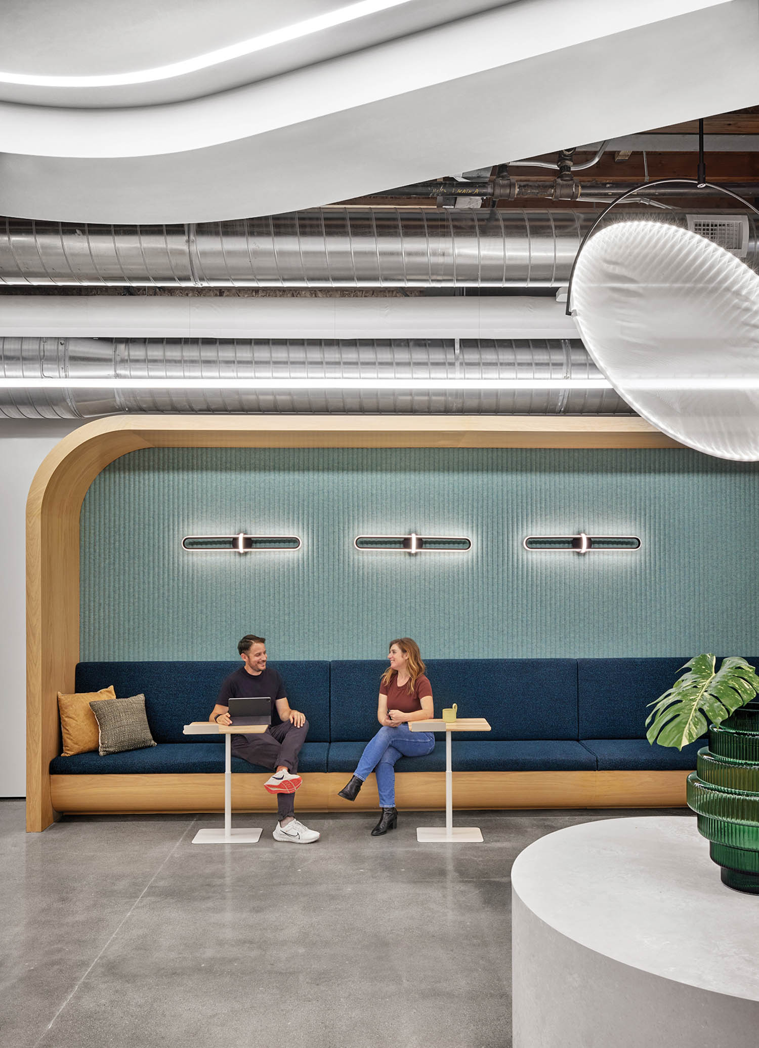 blue banquette seating with white-oak  portal framing the coffee bar area next to a disk-like pendant