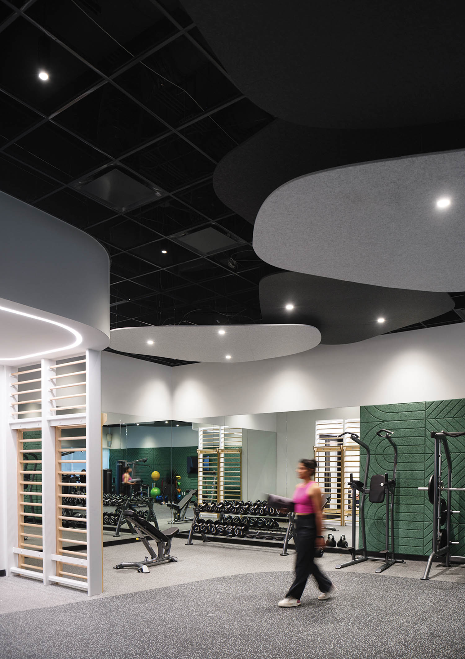 person walking through brightly lit gym with wood-wool paneling