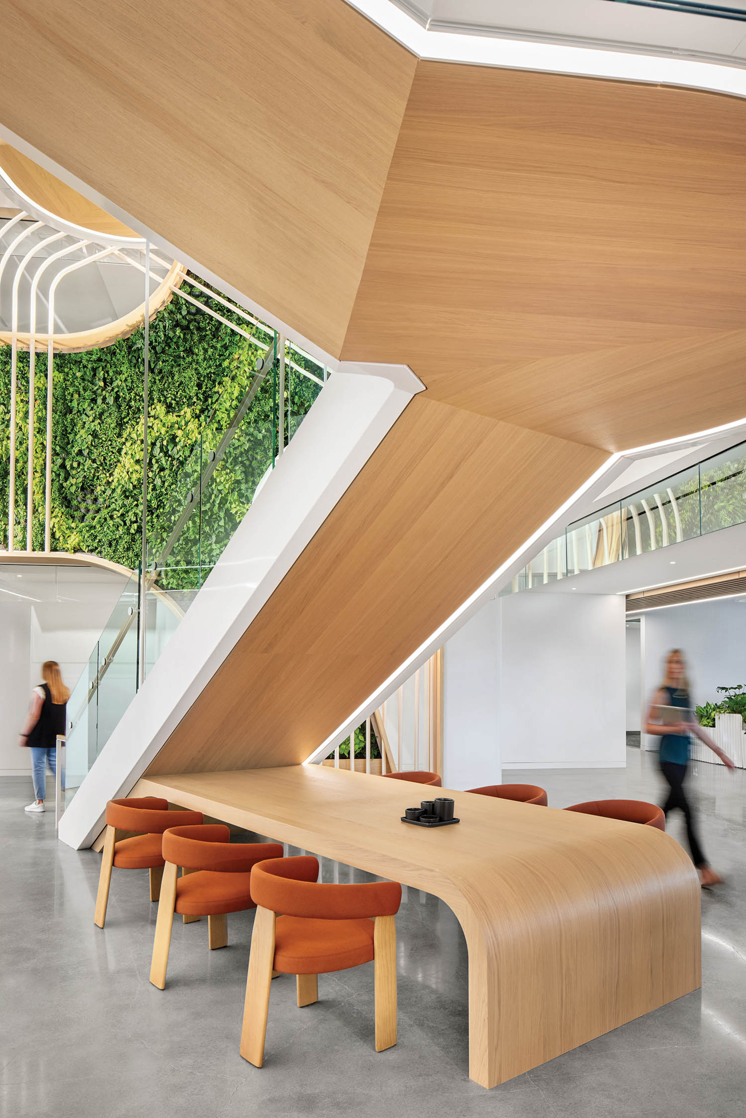 area underneath the stairs with white oak tables and orange chairs