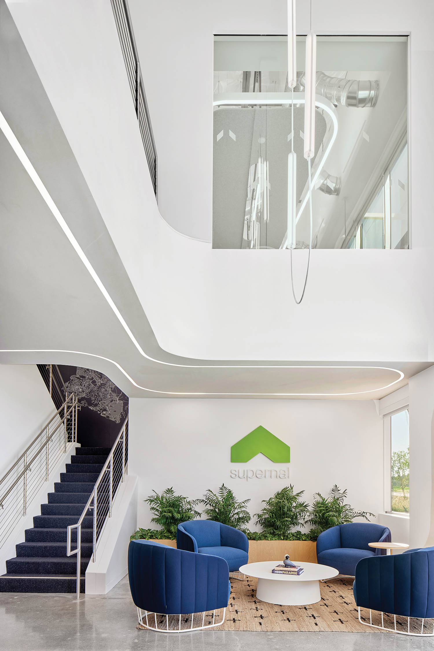 reception area with blue lounge chairs, plants and view of the second story