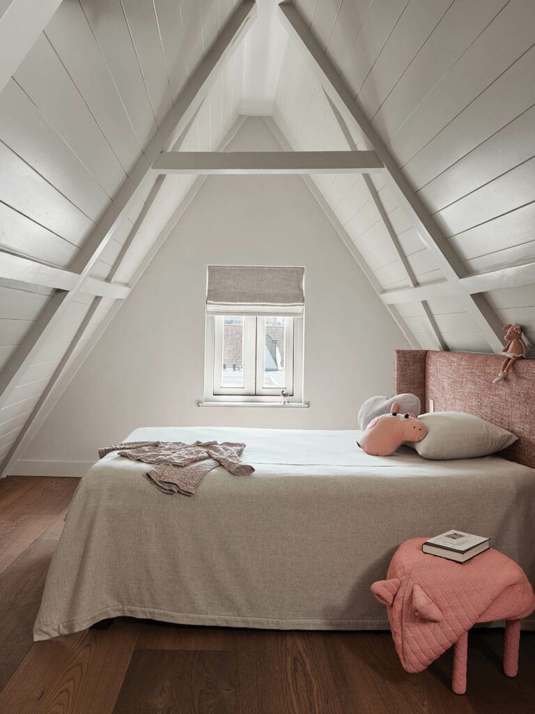 loft bedroom with tall pointed ceiling and pink accessories