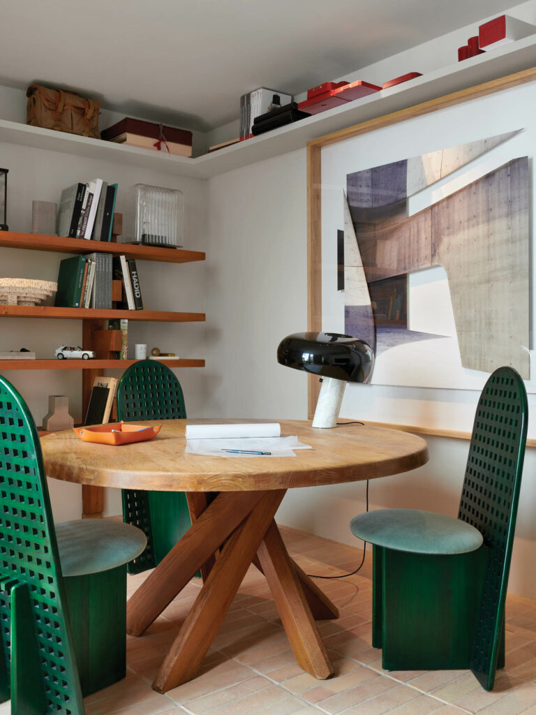 corner of office area with green chairs, wooden table and wooden shelves