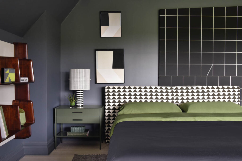 a bed with a green covering and a houndstooth headboard in black and white