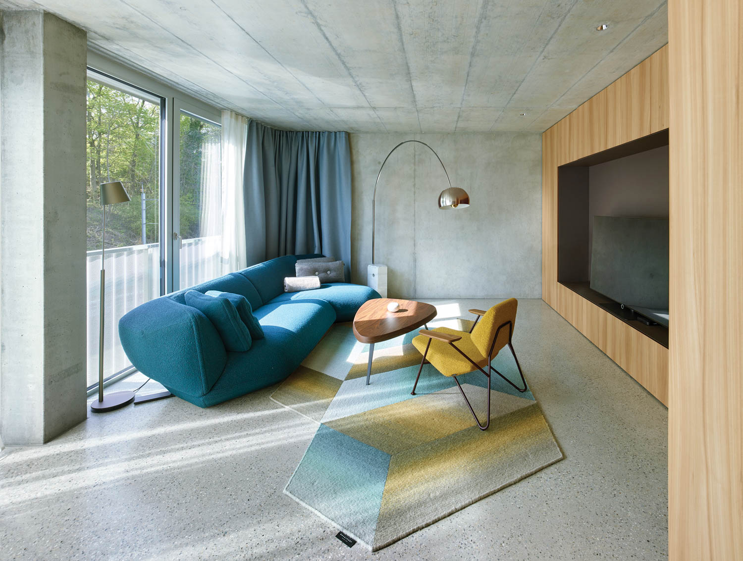 living room with wooden paneled walls, blue couch and geometric rug