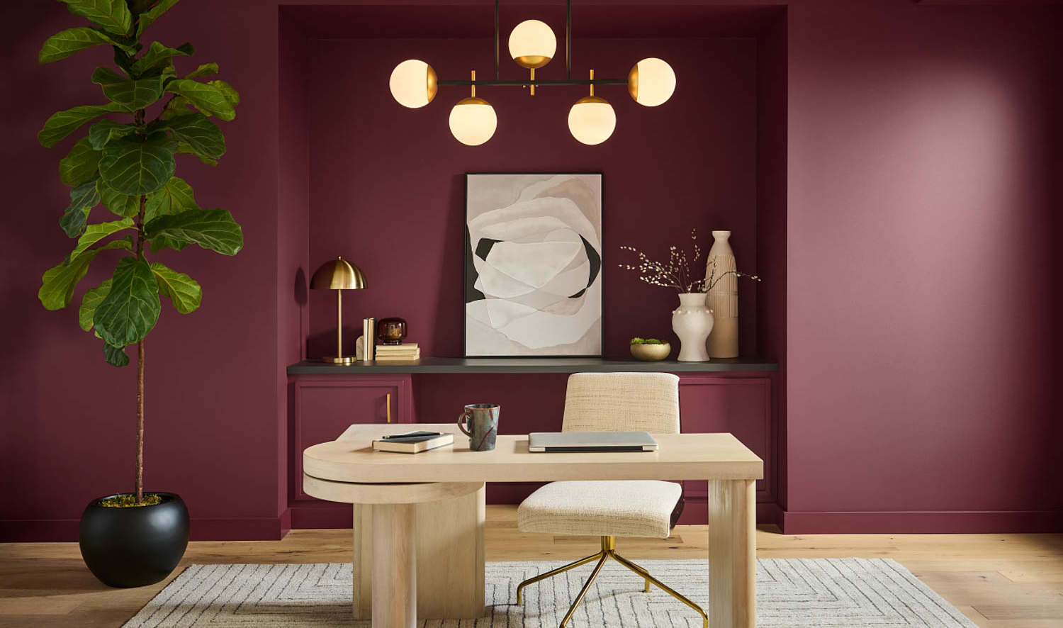 home office with dark red walls, wooden desk and chandelier